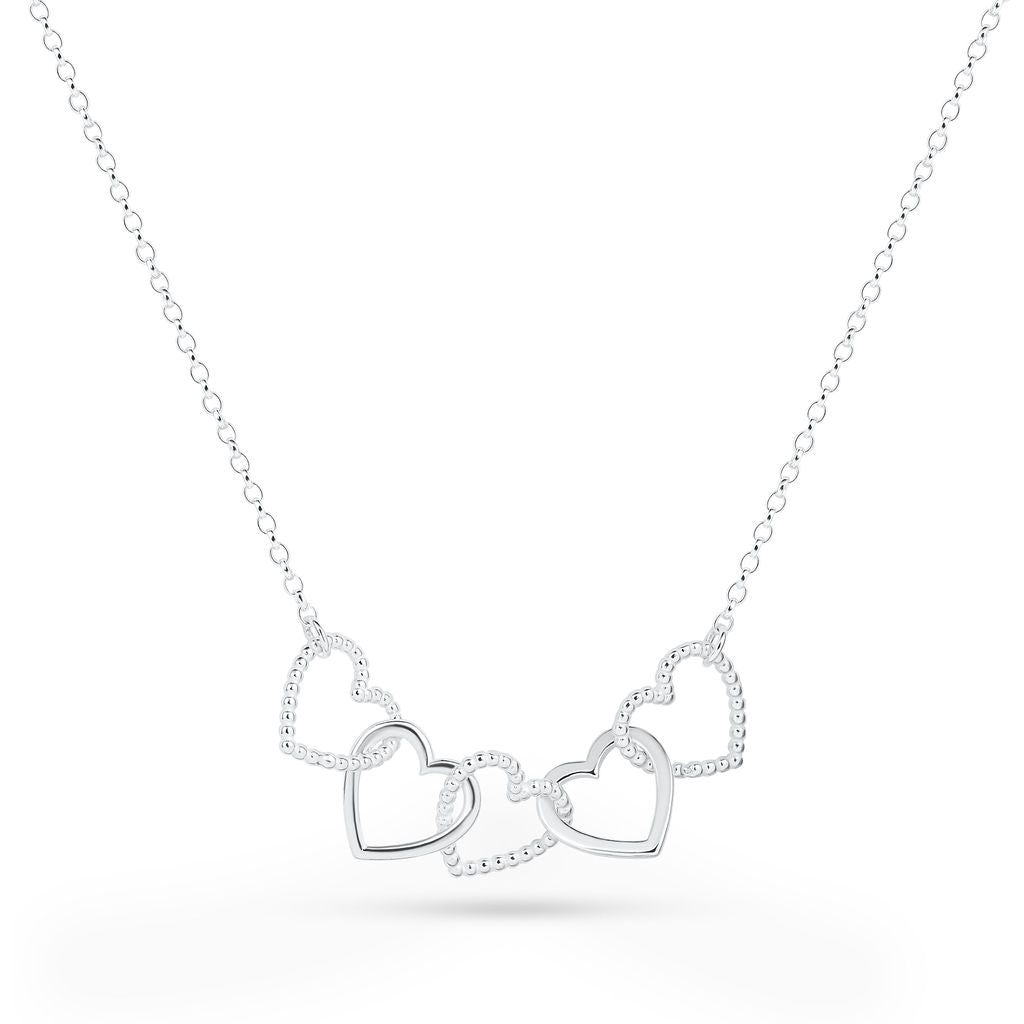 A silver Cariad necklace by Elin Mair featuring three interlocking open heart pendants, some outlined with small pavé-set stones, on a delicate link chain against a white background.